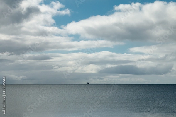 Fototapeta Vast seascape with a lone ship on the horizon. Big sky.
