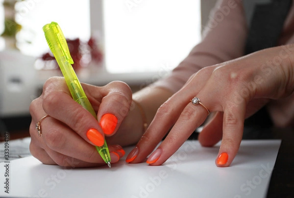 Obraz female hands with bright manicure write on paper