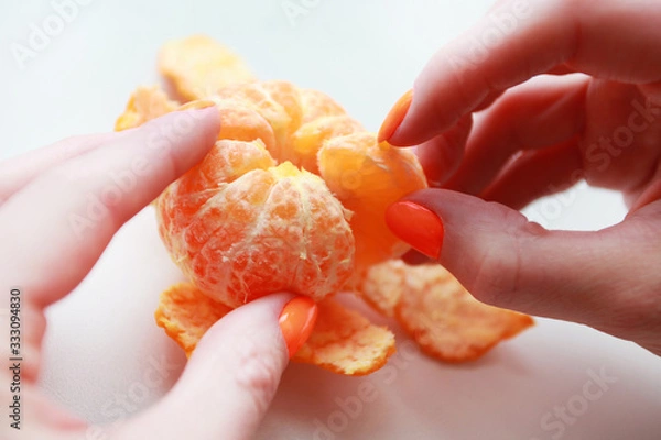 Obraz female hand with bright manicure holds a mandarin