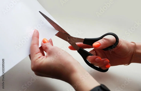 Obraz female hand holds cuts with scissors