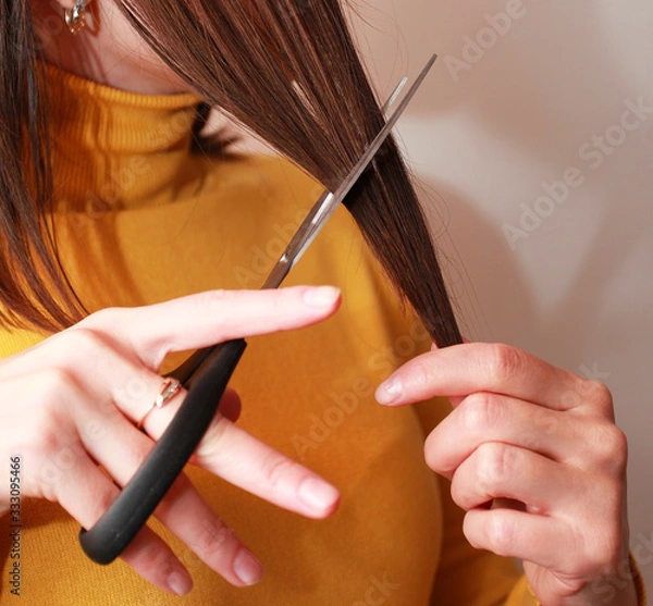 Obraz female hand holds cuts with scissors