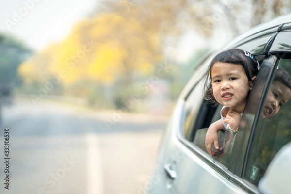 Fototapeta Cute girl sitting in car against blossom Tabebuia aurea tree background