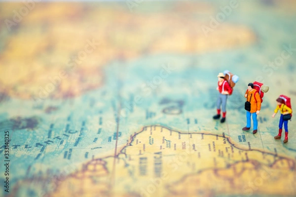 Fototapeta Miniature people: Group of backpacker on vintage world map using as business trip traveler adviser agency or explorer on earth background concept.