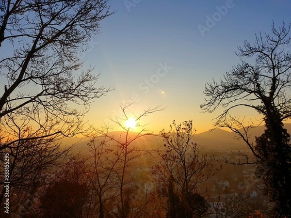 Obraz Sunset at the Schlossberg in Graz with a view of the west of Graz as well as mountains and trees
