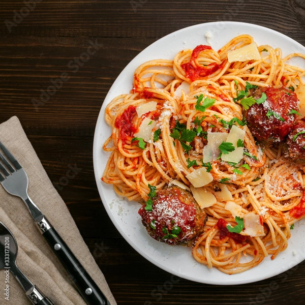 Obraz Pasta with meatballs, parmesan and tomato sauce on a plate.  Homemade Italian spaghetti on a rustic wooden table. Top view shot directly above.