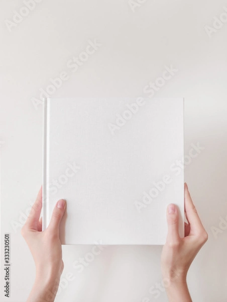 Fototapeta White book mockup. Square empty book. Album with clean pages in hands of woman. Clean book cover mockup