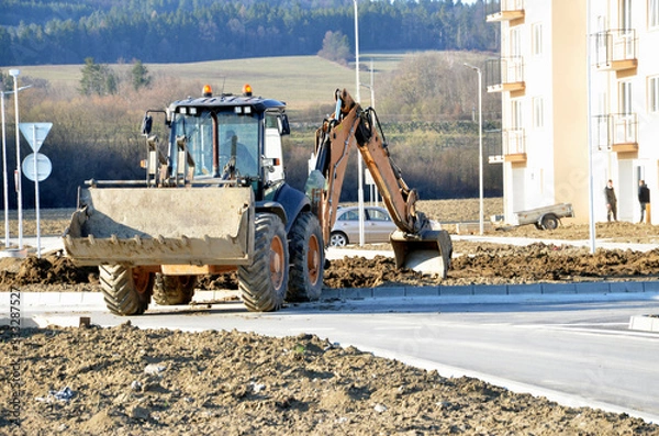 Fototapeta Wheel excavator works on ground shaping in front of the flathouse