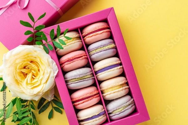 Fototapeta Colorful macaroons and flowers. Sweet macarons in gift box. Top view