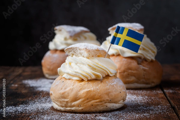 Obraz Traditional Scandinavian cream and almond paste filled cardamom bun Semlor with a Swedish flag.