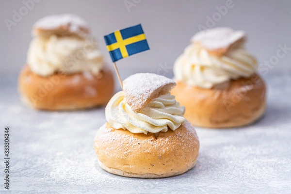 Obraz Traditional Scandinavian cream and almond paste filled cardamom bun Semlor with a Swedish flag.