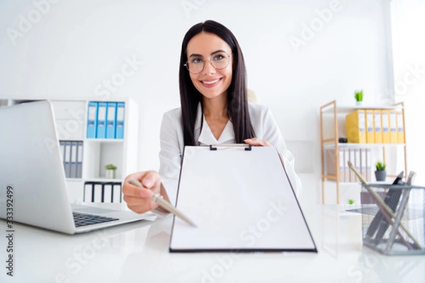 Fototapeta Photo of beautiful professional doc lady hold clipboard with hospital contract insurance showing patient place for signature wear white lab coat sit chair office clinic indoors