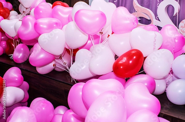 Obraz A large number of inflated multicolored heart-shaped balloons are stacked in bulk in the corner of the room for the upcoming holiday, close-up, copy space, toned.