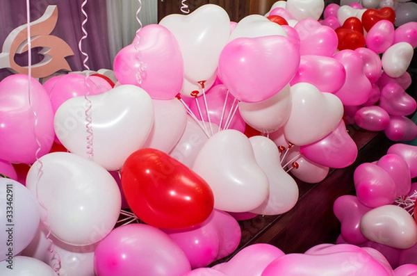 Obraz A large number of inflated multicolored heart-shaped balloons are stacked in bulk in the corner of the room for the upcoming holiday, close-up, copy space.