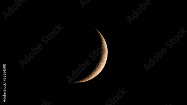 Obraz Astronomy: Tiny moon crescent full of small craters in the dark sky of the night.