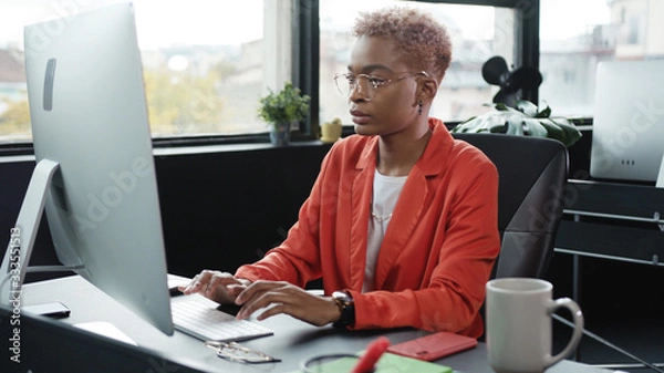 Obraz Young ambitious woman office employee typing keyboard on desktop computer completing tasks working in contemporary coworking space.