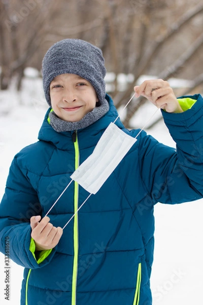 Fototapeta The danger of coronavirus. A boy on a walk walks in a medical mask on his face