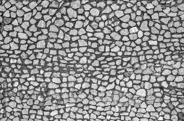 Obraz A fragment of a wall made of stones of different sizes held together with mortar, black and white, close-up, copy space.