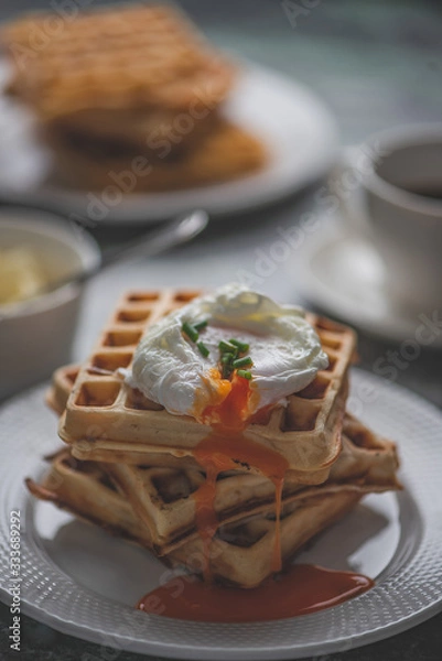 Fototapeta Waffles (Side View) topped with poached egg for breakfast.