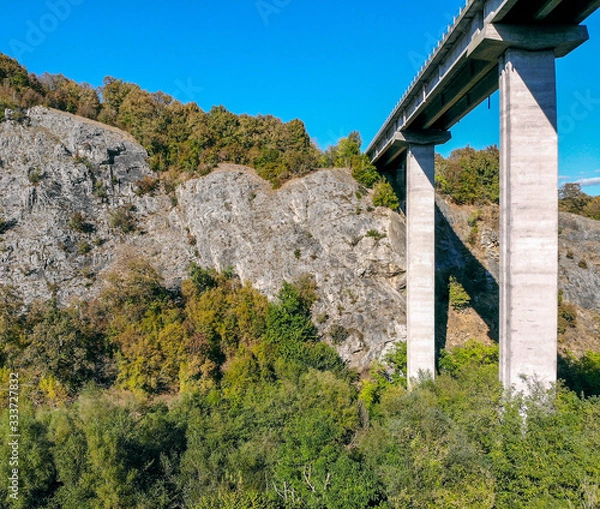 Fototapeta Created by dji camera. An automobile bridge on high pylons through a deep gorge in the mountains.