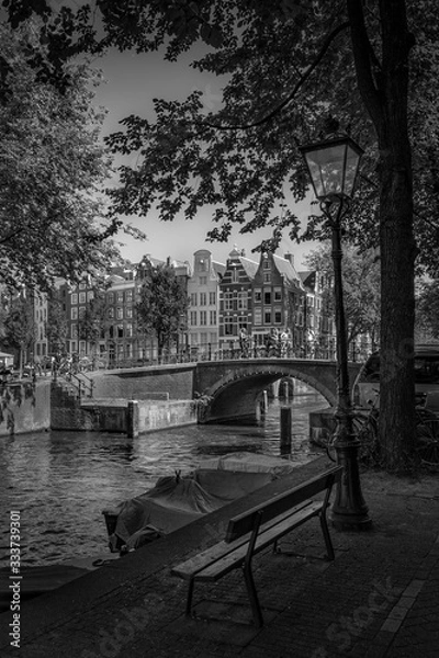 Fototapeta A view of buildings bridge and boats along the Amsterdam canal.