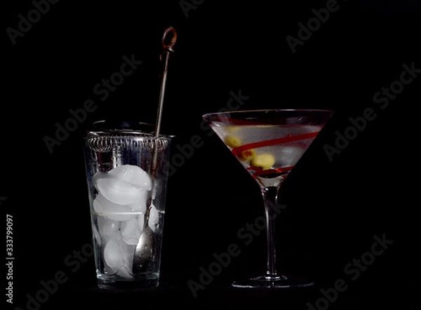 Fototapeta Martini on a Black Background, Stirred, Not Shaken, with Three Olives, and the Mixing Glass, Spoon, Strainer, and Ice