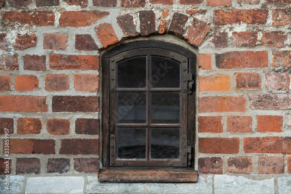 Fototapeta Antique wooden window with metal fittings and hinges in an old red brick wall of an ancient European castle.