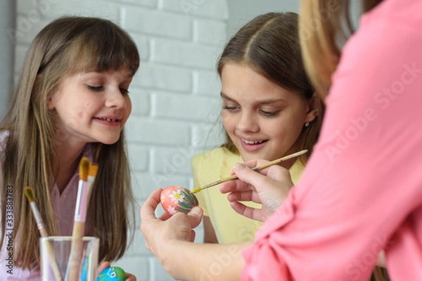 Fototapeta Children watch mom paint Easter eggs beautifully