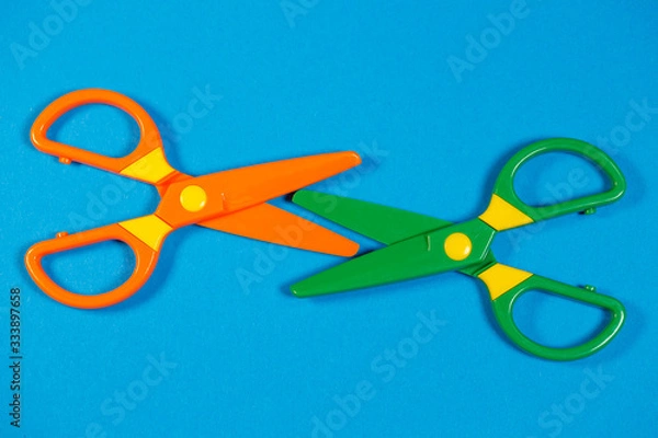 Fototapeta Children's plastic scissors for cutting paper figures on a colored background