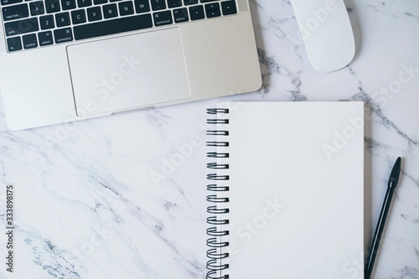 Fototapeta Modern marble office desk table with laptop and other supplies. Blank white notebook page for input text or entry short note, copy space for creative content, ads and design . Top view, flat lay.