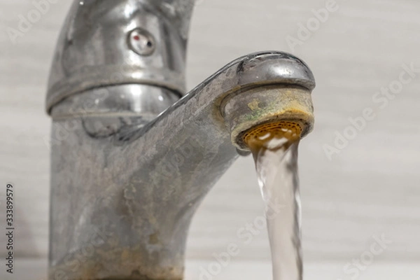 Obraz Old Bathroom Sink Faucet contaminated with calcium and grime. Hard water flows from an old tap aerator.