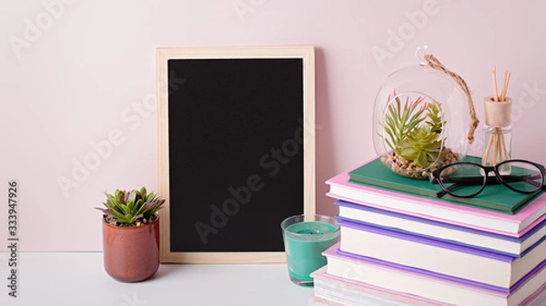 Fototapeta Books stack, eyeglasses, house plants succulents and fragrant candle and sticks. Background for World Book Day. Still life with stack of colorful books and home interior decor