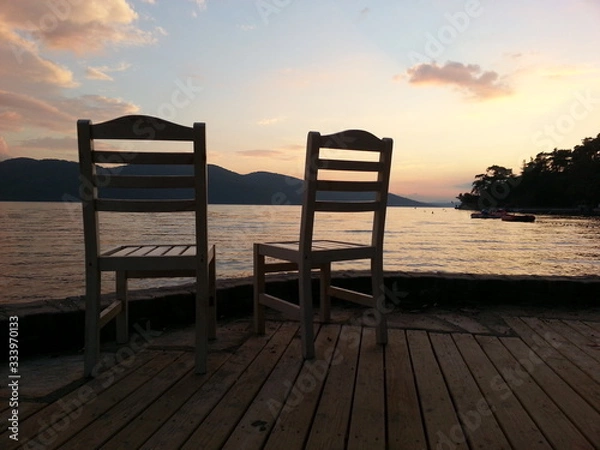 Fototapeta the two empty chair at the sunset between the coast