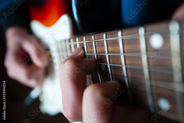 Fototapeta Male hands playing electric solo guitar with closeup photo. Learning musical instrument, music shop or school, blues bar or rock cafe, having fun enjoying hobby concept