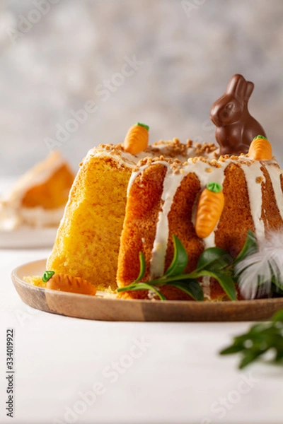 Fototapeta Easter lemon cake with icing and easter decoration. Easter gugelhupf cake with marzipan carrots and chocolate easter bunny