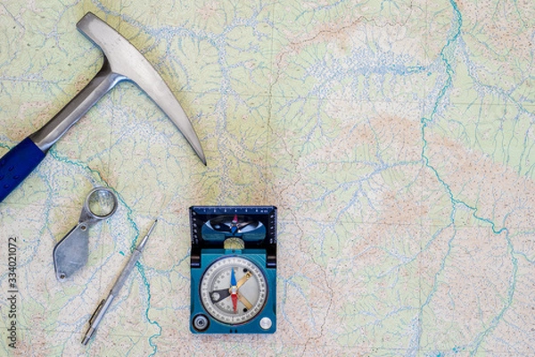 Fototapeta The tools of the geologist laid out on a topographic map. Background