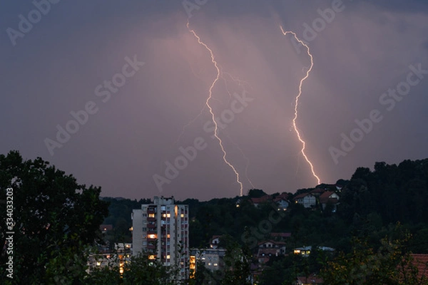 Fototapeta Lightning over the city at the summer storm. Dramatic, breathtaking atmospheric natural phenomenon.Beautiful dark storm sky. Clouds and thunder lightnings.Bright lightning in the black sky