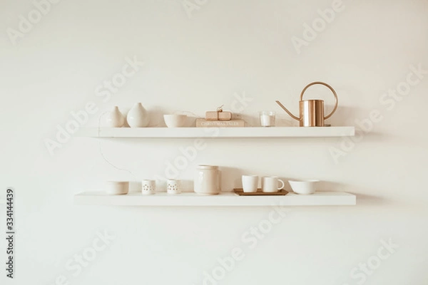 Fototapeta Kitchenware utensils on shelf on white background. Ceramic mugs, cups, teapot, tray. Minimal interior design concept.