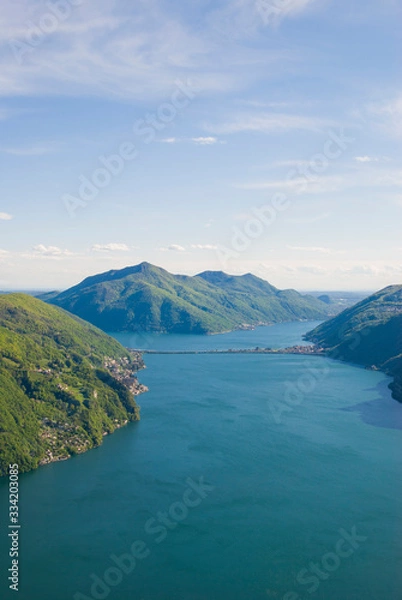 Fototapeta A top view of Lake Lugano, Switzerland from the height of Mount Monte Bre. Beautiful mountain scenery on a sunny summer day. View of Lake Lugano and the Alpine mountains covered with green plants.