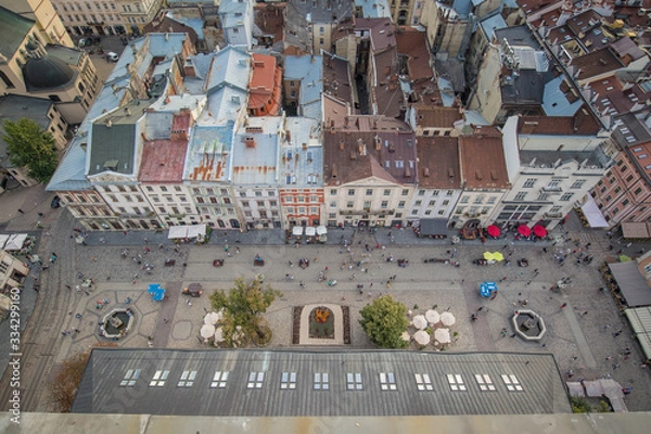 Fototapeta Bird view from the top of the city hall tower in Lviv, Ukraine, looking down to the town square and houses around. Visible people and two beautiful fountains.