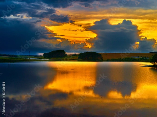 Fototapeta Beautiful summer sunset over the lake. Reflection of sunset in the water. Sunny summer evening.