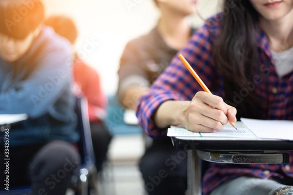 Fototapeta high school,university student study.hands holding pencil writing paper answer sheet.sitting lecture chair taking final exam attending in examination classroom.concept scholarship for education abroad