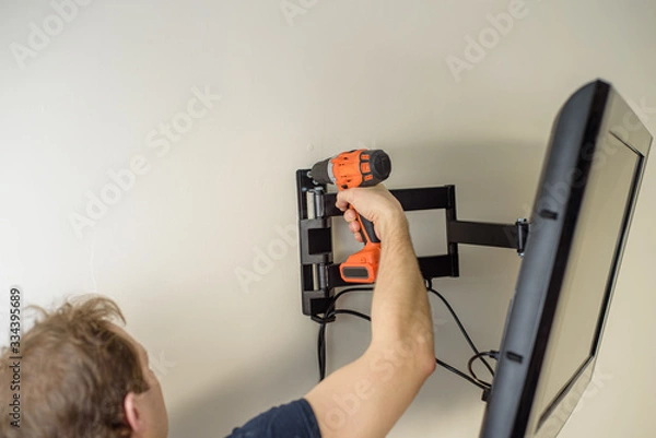 Fototapeta Man hands installing mount TV on the wall