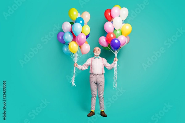 Fototapeta Full size photo of positive cheerful old man hipster hold many air balls enjoy festive occasion event wear good look trousers brown shoes isolated over teal color background