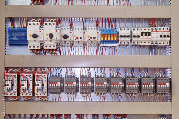 Fototapeta Electrical contactors or starters, motor protection circuit breakers, intermediate relays are arranged in several rows in the electrical Cabinet. Components are connected by electrical wires, cables.