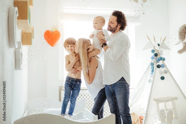 Obraz Four family member playing together with two cute boys in a sunny bright room. Enjoying sunny days at home during quarantine. Perfect parenting relationship. Stay home together. Family time