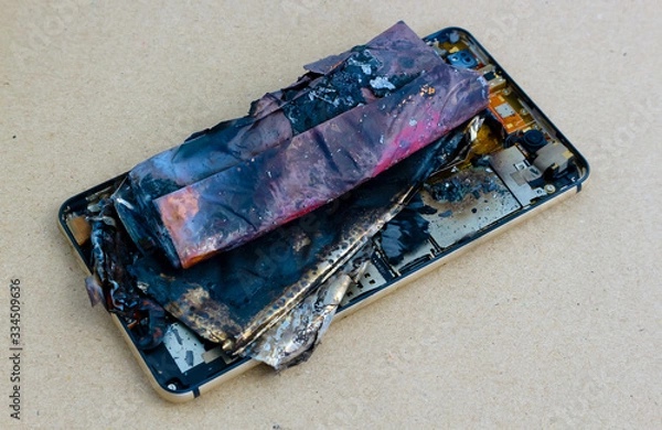 Fototapeta smartphone battery explodes on a brown paper background.