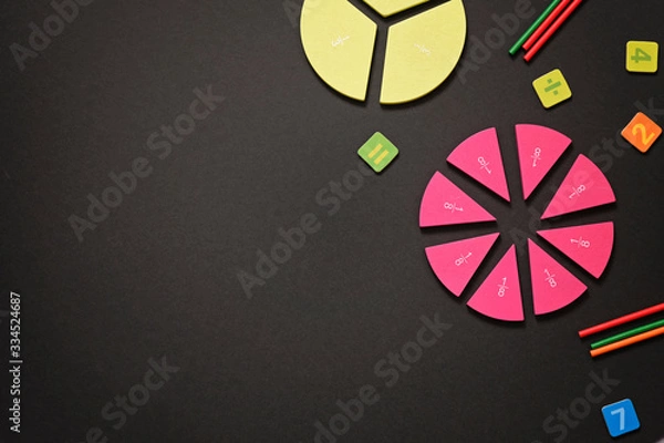 Fototapeta Mathematics background - fractions on black table, close up. Dividing fractions, math concept.