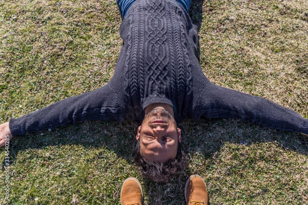 Obraz relaxed and happy dark-haired man lying on the grass with open arms