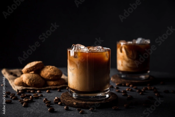 Fototapeta A horizontal photo of 2 rocks glasses with cold iced coffee with milk, coffee beans around, cookies, dark background, deep shadows