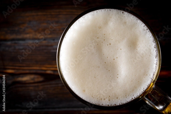 Fototapeta white foam of light beer on a dark background, top view